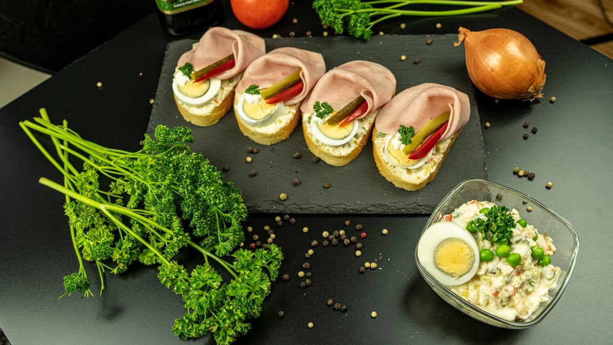Delicious open-faced ham sandwiches with eggs, garnished with parsley, on a slate.