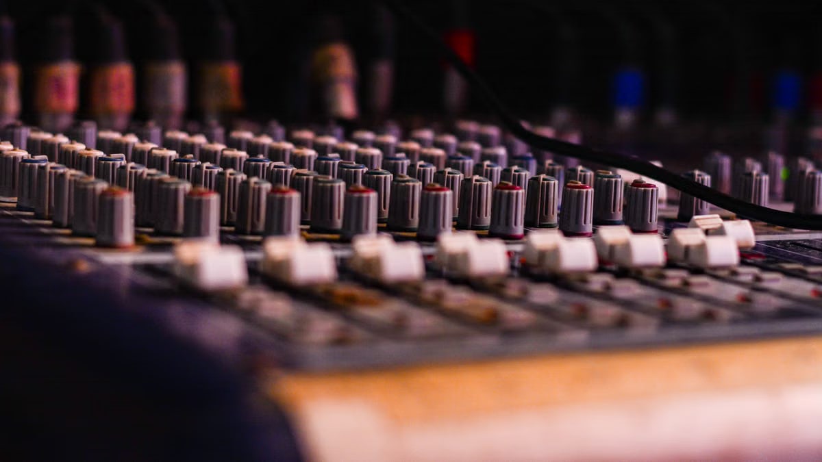 Close-up of a professional audio mixing console with knobs and sliders, essential for music production.
