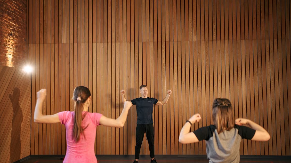 Instructor guiding two women in a gym workout session. Indoor fitness training.